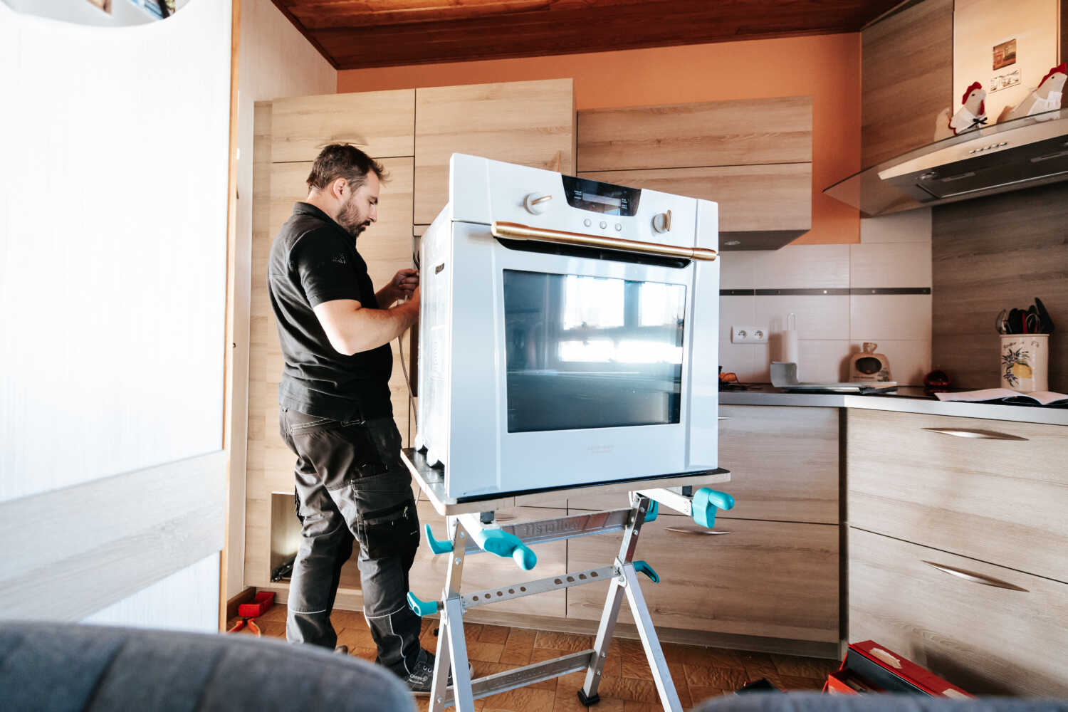 Entreprise BOUVIER ATEs entrain de réparer un électroménager d'une cuisine à Rumilly